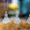 Close-up of beautiful silver necklaces with intricate designs hanging with a blurred background.